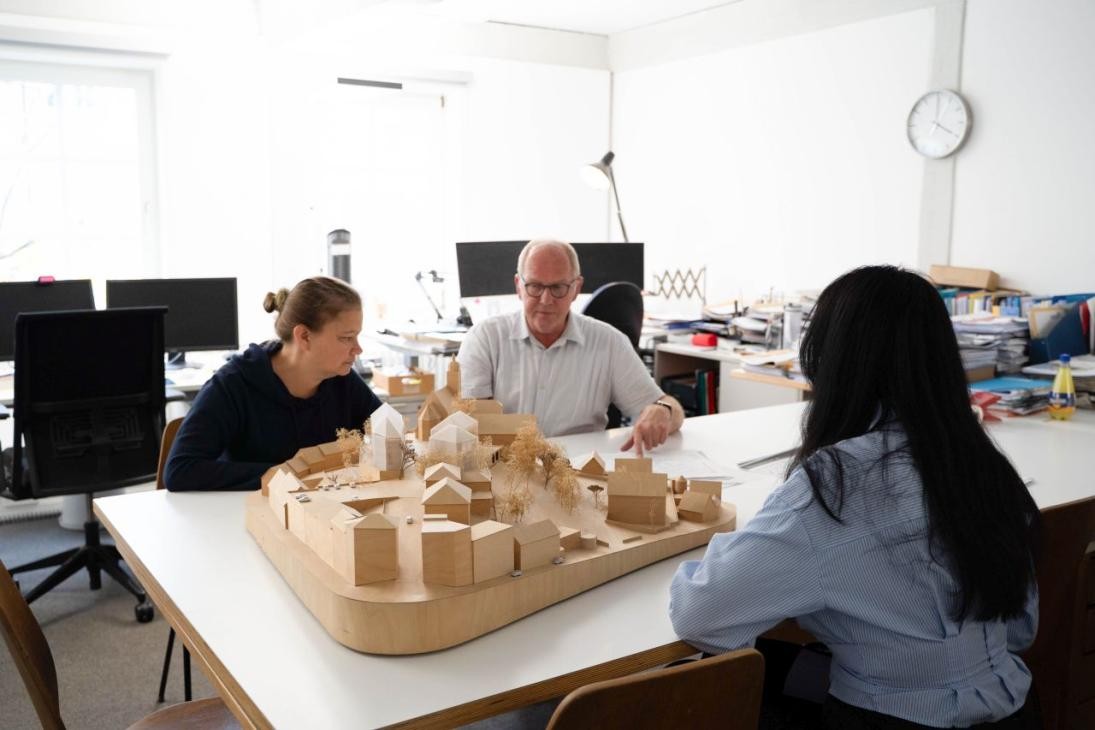 3 Mitarbeiter schauen die Stadtplanung im Modell an