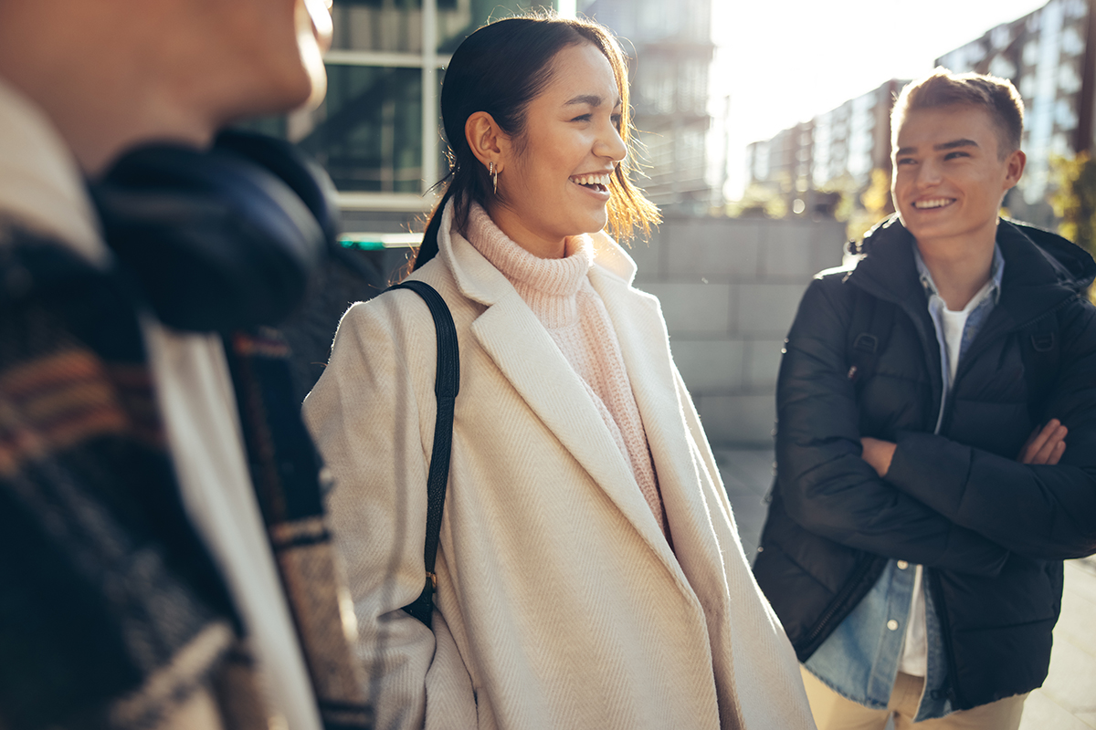 Eine Schülerin nach Schulschluss mit Mantel auf dem Schulcampus