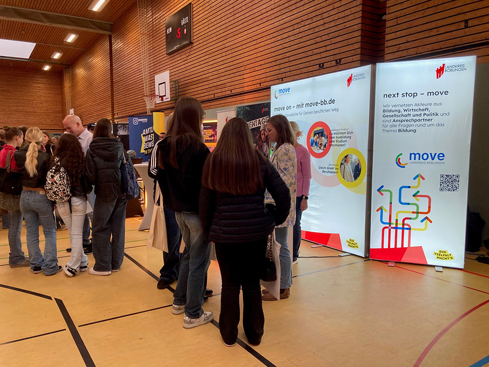 Jugendliche auf einer Messe mit Messeständen im Hintergrund