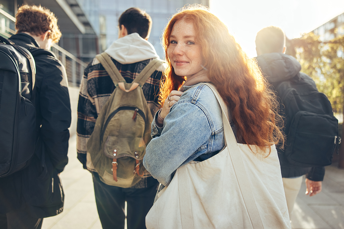 Schülerin auf einem Schulcampus schaut lächelnd zurück