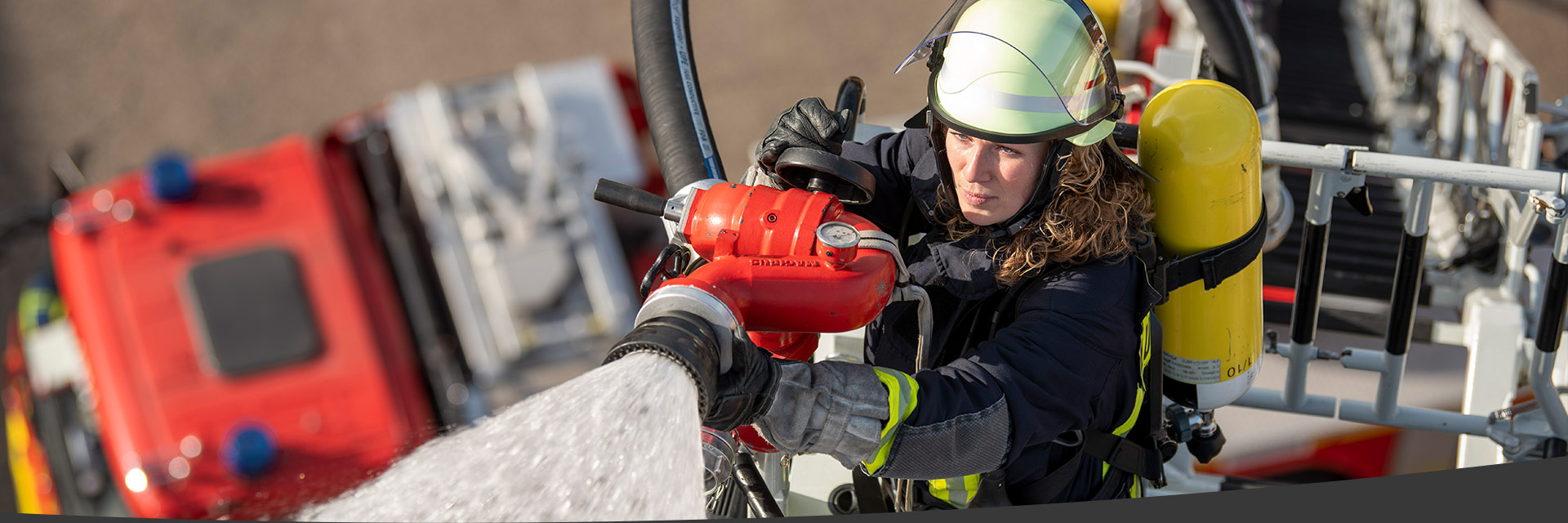 Feuerwehrfrau mit dem Schlauch auf der Drehleiter