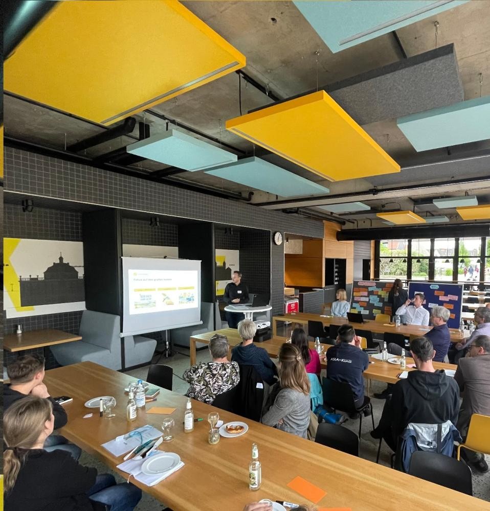 Teilnehmenderunde hören dem Vortrag zu