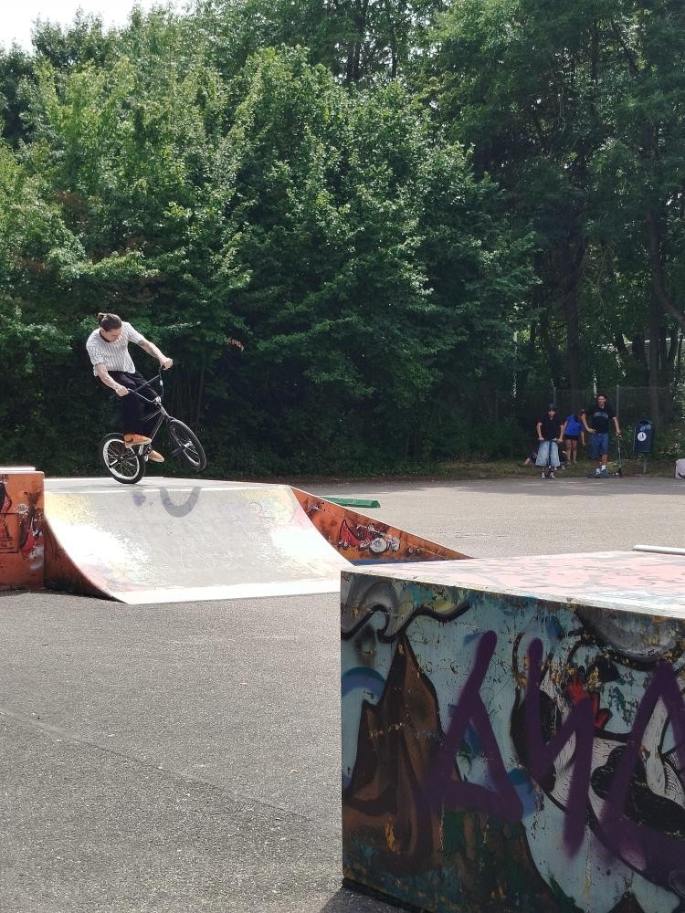 Jugendliche Person mit Fahrrad auf Rampe 