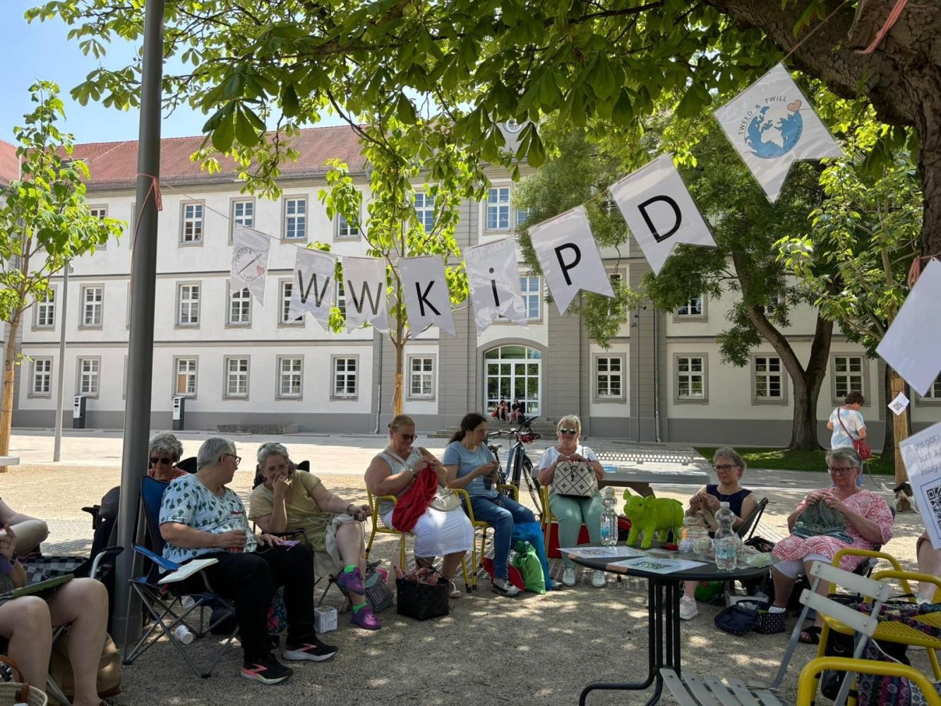 Personen sitzen im Schatten und stricken auf dem Arsenalplatz