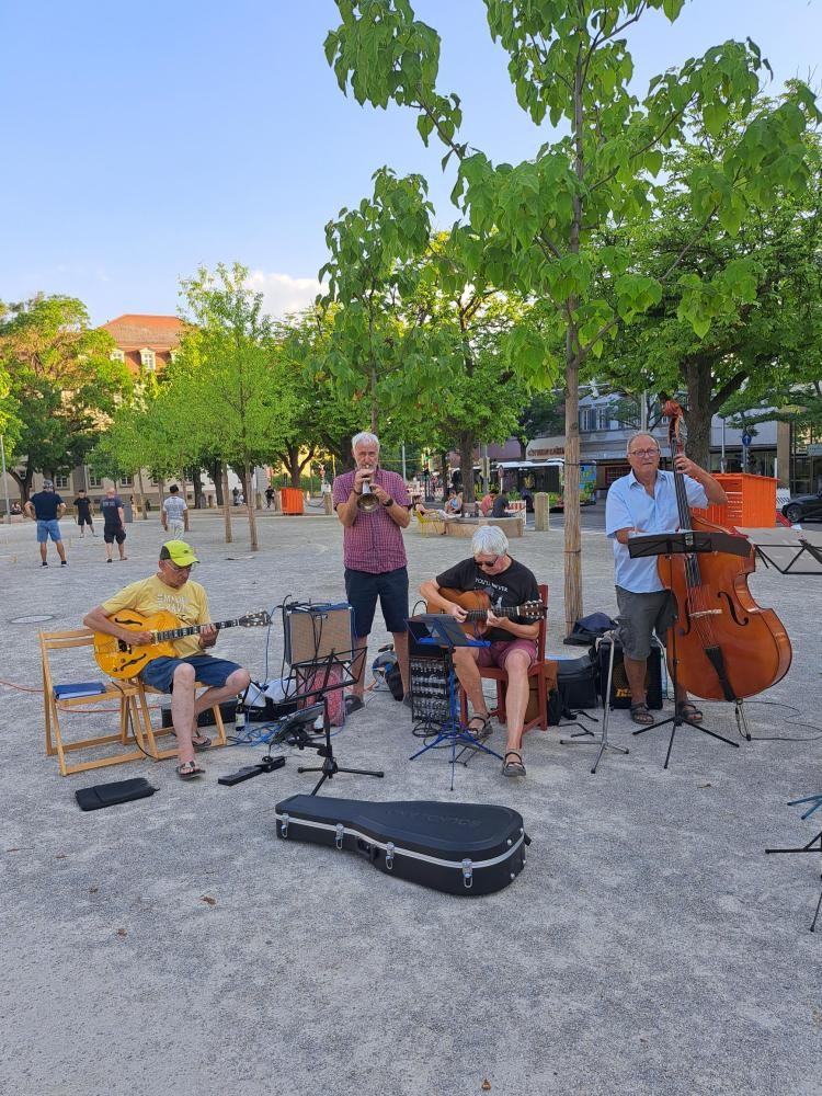 Zwei Guitarristen, ein Trompeter und ein Kontrabassist spielen am Arsenalplatz