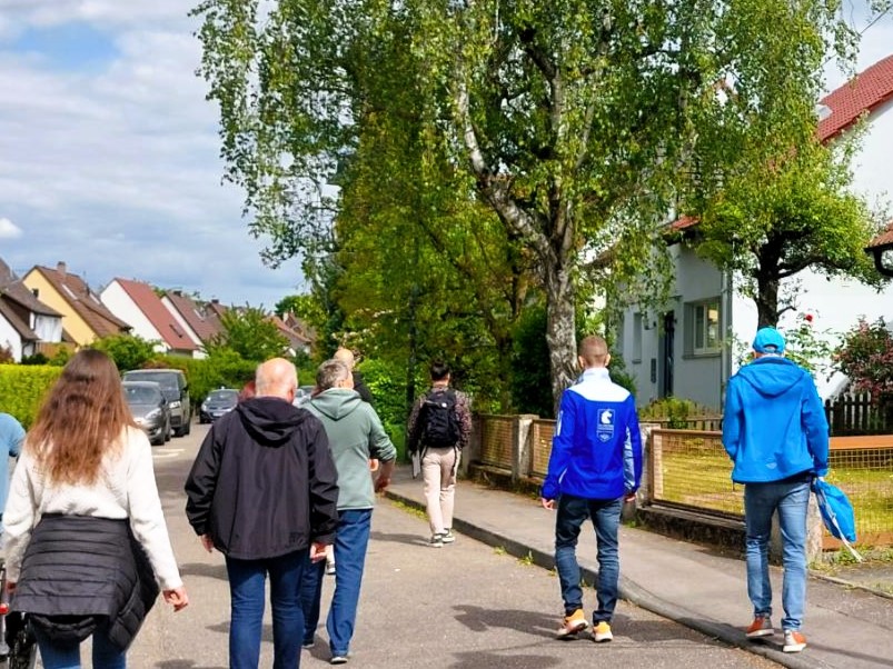 Personen laufen auf der Straße an Häusern entlang