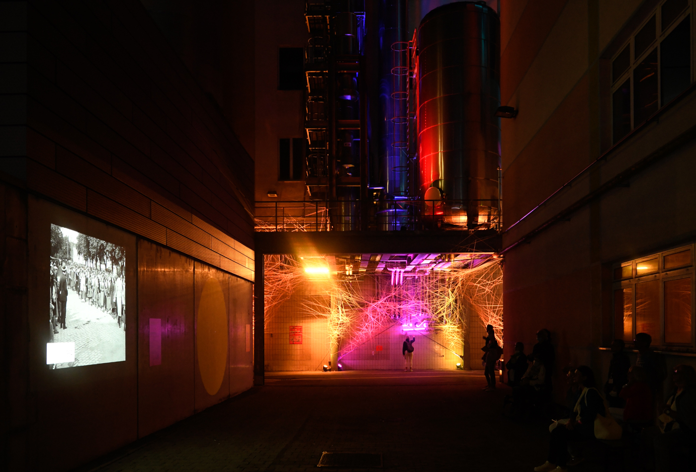 Die Fadeninstallation "Blast from the Past von der Künstlerin Ines Fiegert strahlt in der Dunkelheit in gelben und rosa Farben.