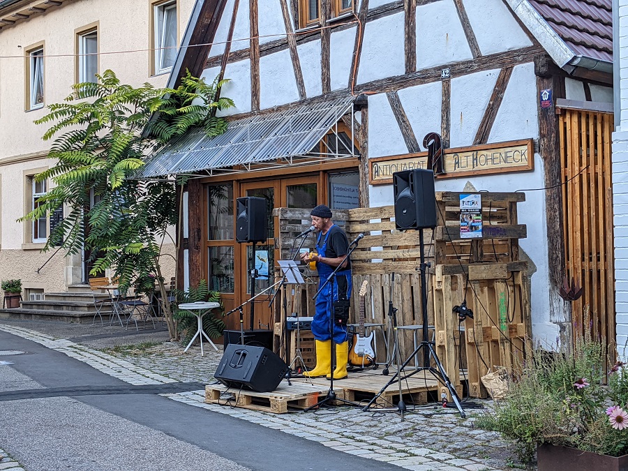 Schauspieler mit Gummistiefeln vor Fachwerkhaus