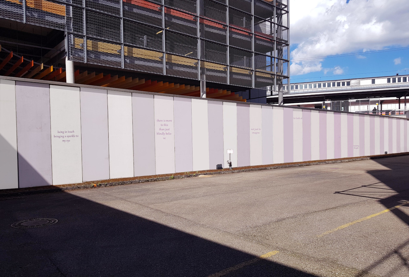 Eine Betonwand mit bunten Streifen und Zitaten ist zu sehen.