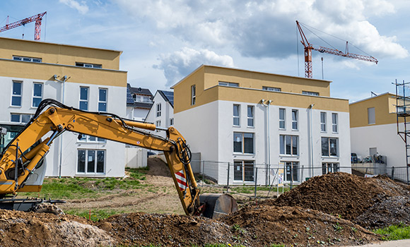 Bagger steht vor Neubauten.