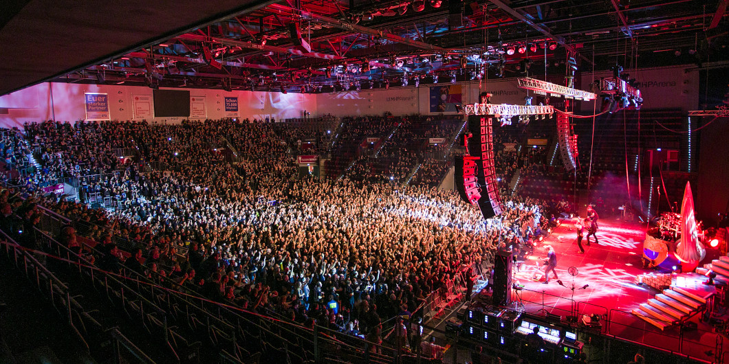 Blick von oben auf ein Konzert in der MHPArena Ludwigsburg. Rechts sieht man die pink beleuchtete Bühne, links den gefüllten Zuschauerraum