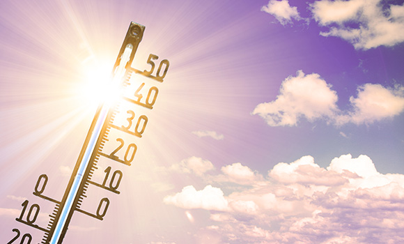 Thermometer vor Himmel mit Sonne.