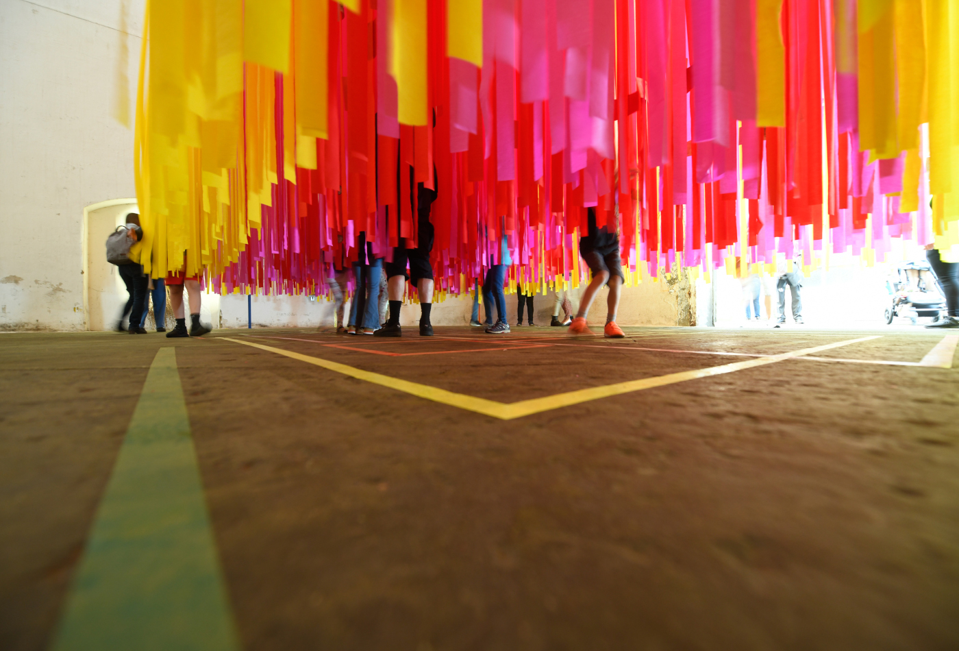 Bunte Krepp-Bänder hängen von der Decke herunter. Dazwischen laufen Menschen.
