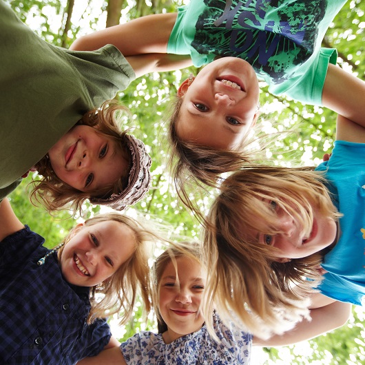 Kinder stehen im Kreis in einem Park und Lachen