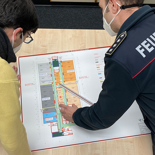 Kameraden der Feuerwehr betrachten einen Brandschutzplan