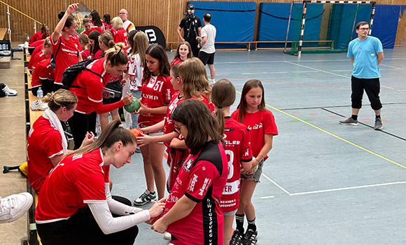 Die Spielerinnen geben den Mädchen Autogramme auf Trikots und Bälle.