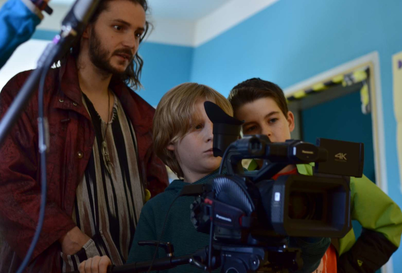 Zwei Jungen und ein Erwachsener an einer Kamera.