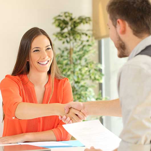 Sachbearbeiterin und Kunde reichen sich die Hände