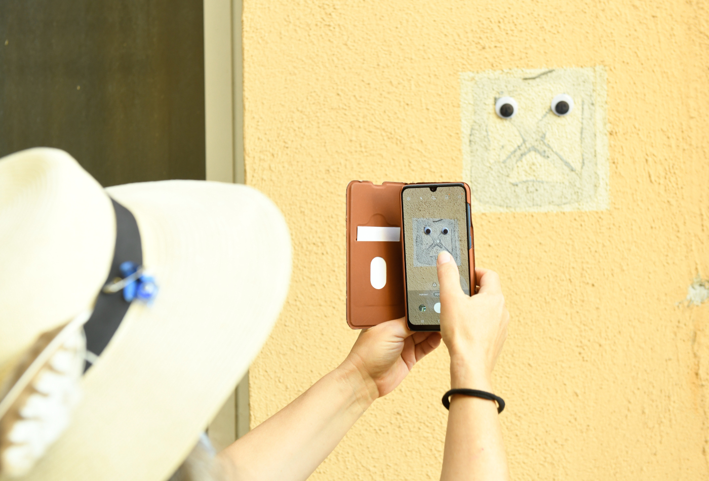 Eine Person mit Hut fotografiert mit dem Handy ein Gesicht auf dem Franck-Areal.