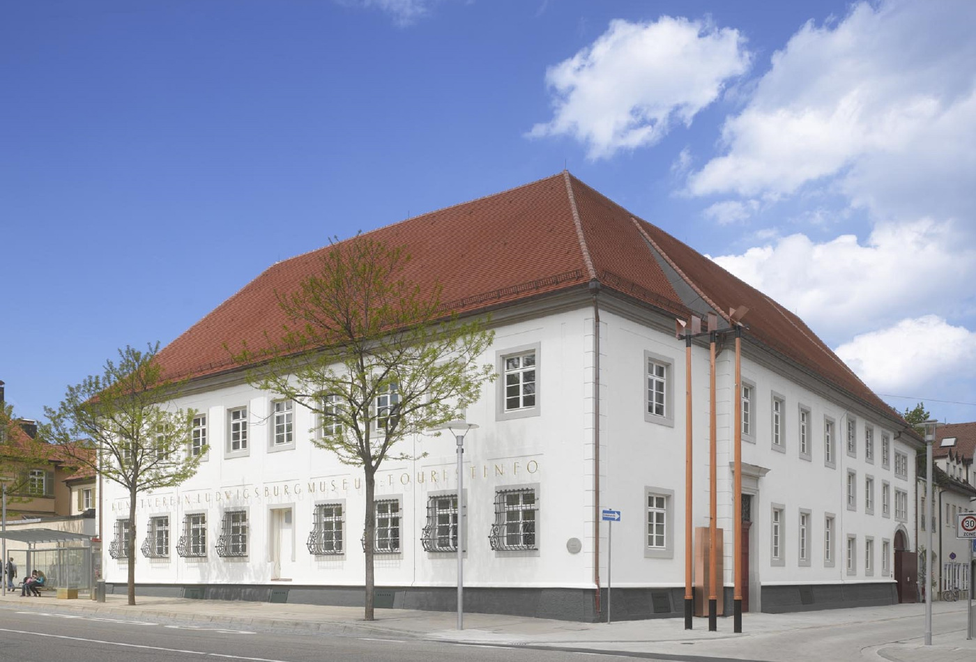 Die Außenfassade des MIK – MUSEUM INFORMATION KUNST mit grünen Bäumen davor.