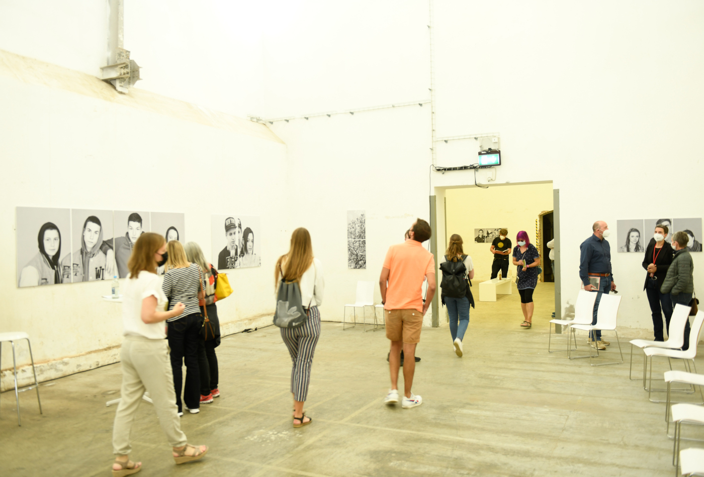 Mehrere Menschen laufen durch einen hohen Raum, in dem Fotografien gezeigt werden.