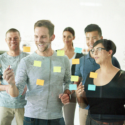 junge Menschen kleben Post-its an eine Glasscheibe