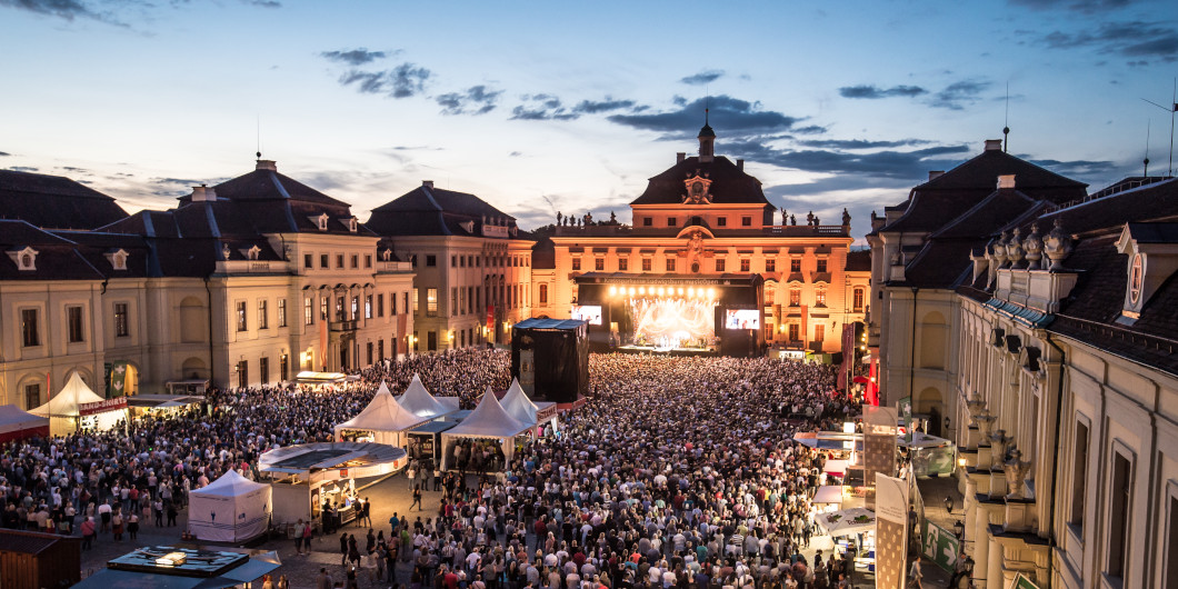 Blick von oben auf den Ehrenhof des Residenzschlosses währender eines Konzertes. Man sieht eine Bühne und eine Menschenmenge