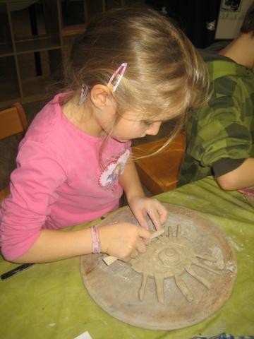 Ein Mädchen bearbeitet eine Tonplatte