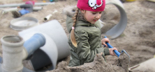 Sandkasten in der KiTa Ein KiTa Kind schaufelt im großen Sandkasten