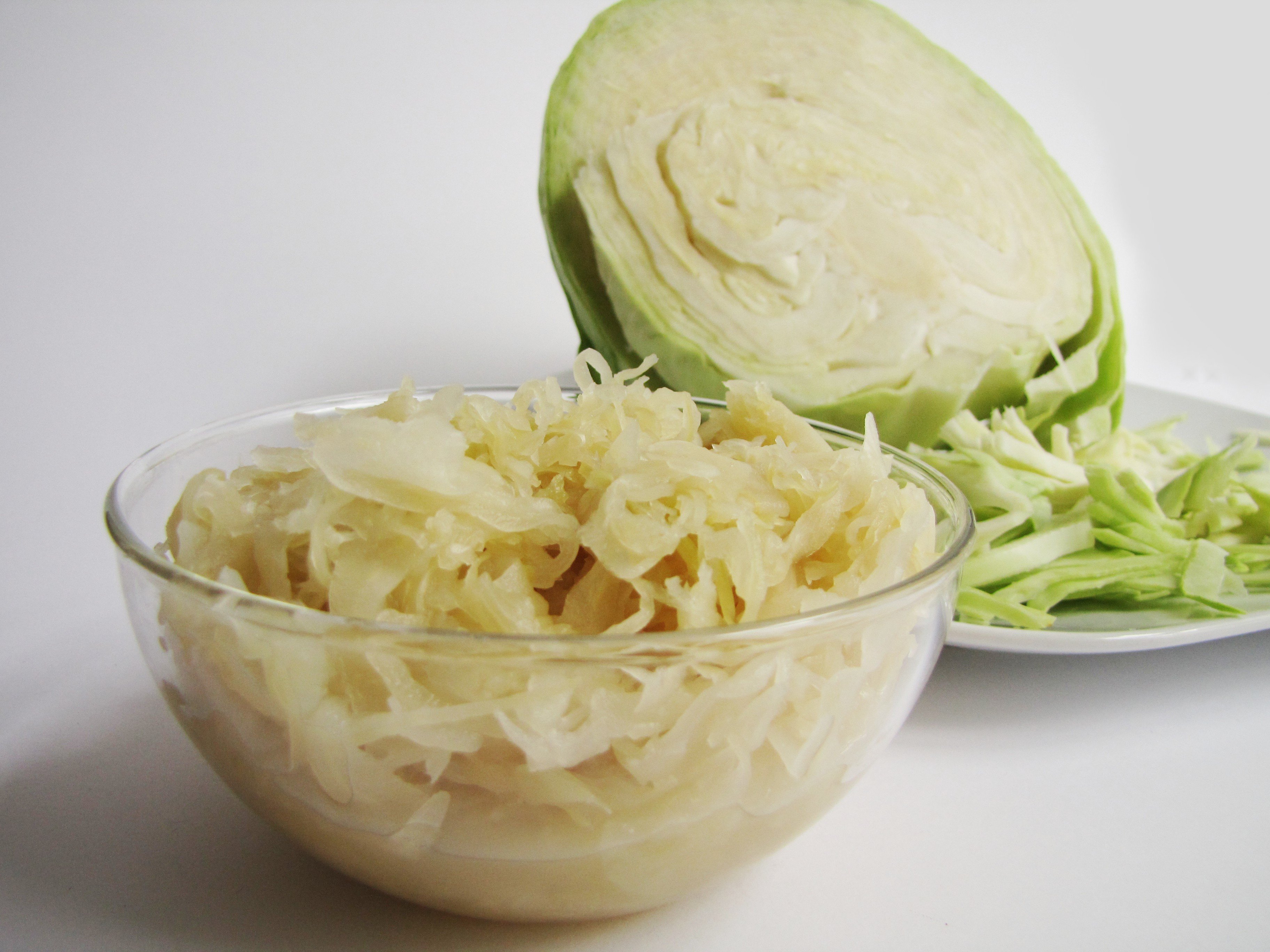 Fit mit Sauerkraut Sauerkraut in einer Glasschüssel, dahinter ein Teller mit Weißkohl
