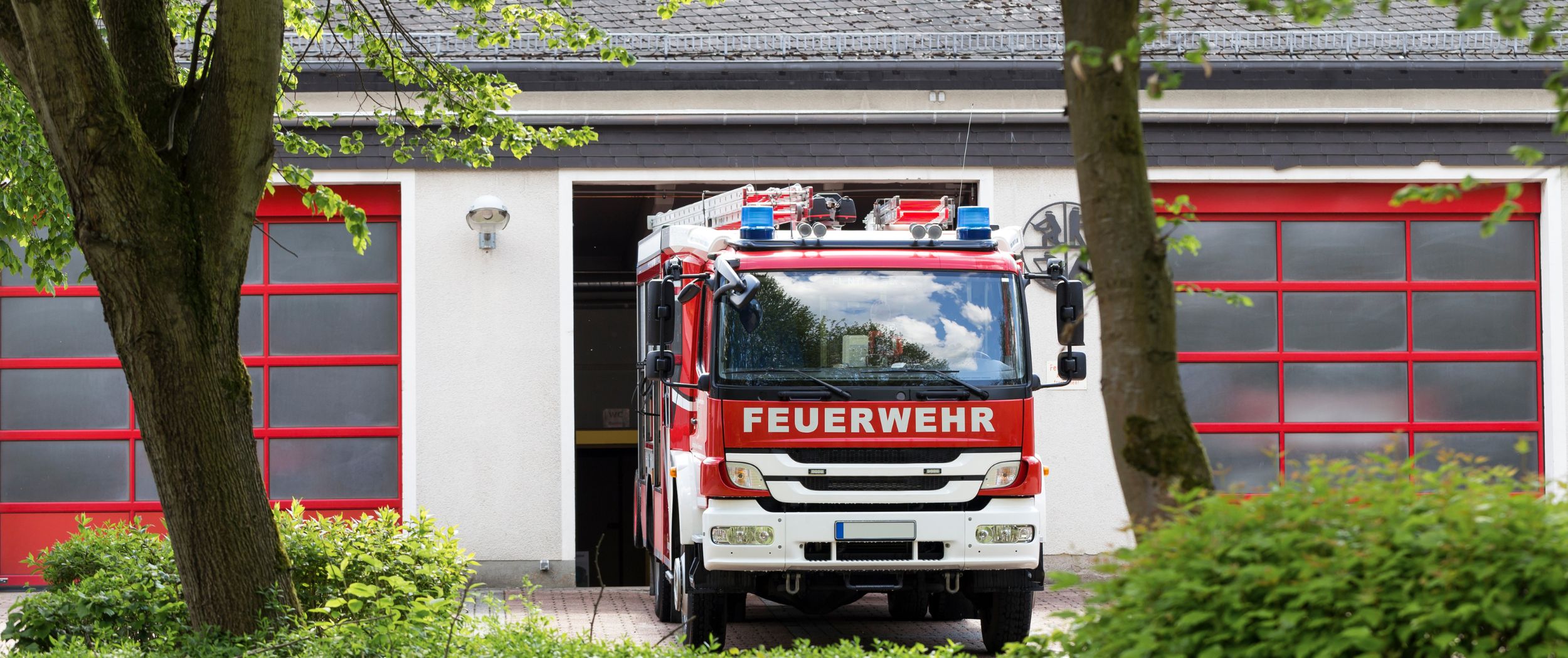 Ein Feuerwehrauto f&auml;hrt aus einer Fahrzeughalle