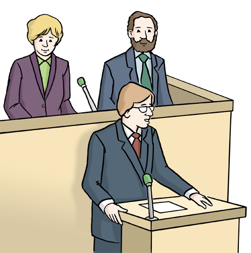 Ein Politiker h&auml;lt eine Rede am Mikrofon. Hinter ihm sitzen zwei weitere Politiker