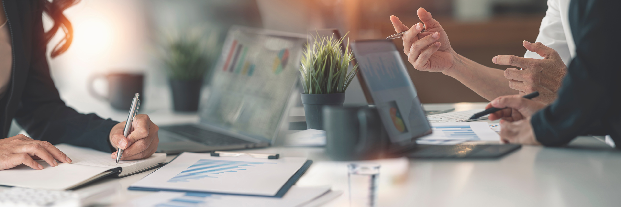 Mehrere Personen besprechen Statistiken mit Laptop und Tablet an einem B&uuml;rotisch