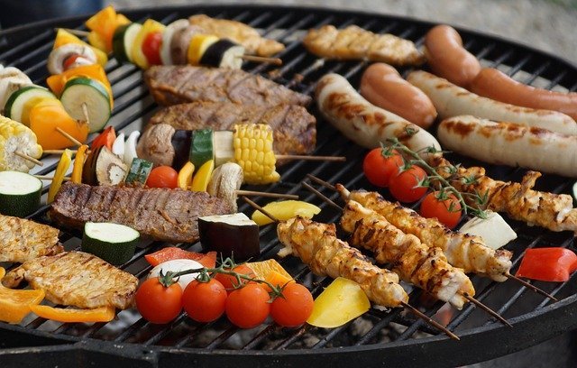 Fleisch, Wurst und verschiedene Gem&uuml;se auf einenm Grillrost 