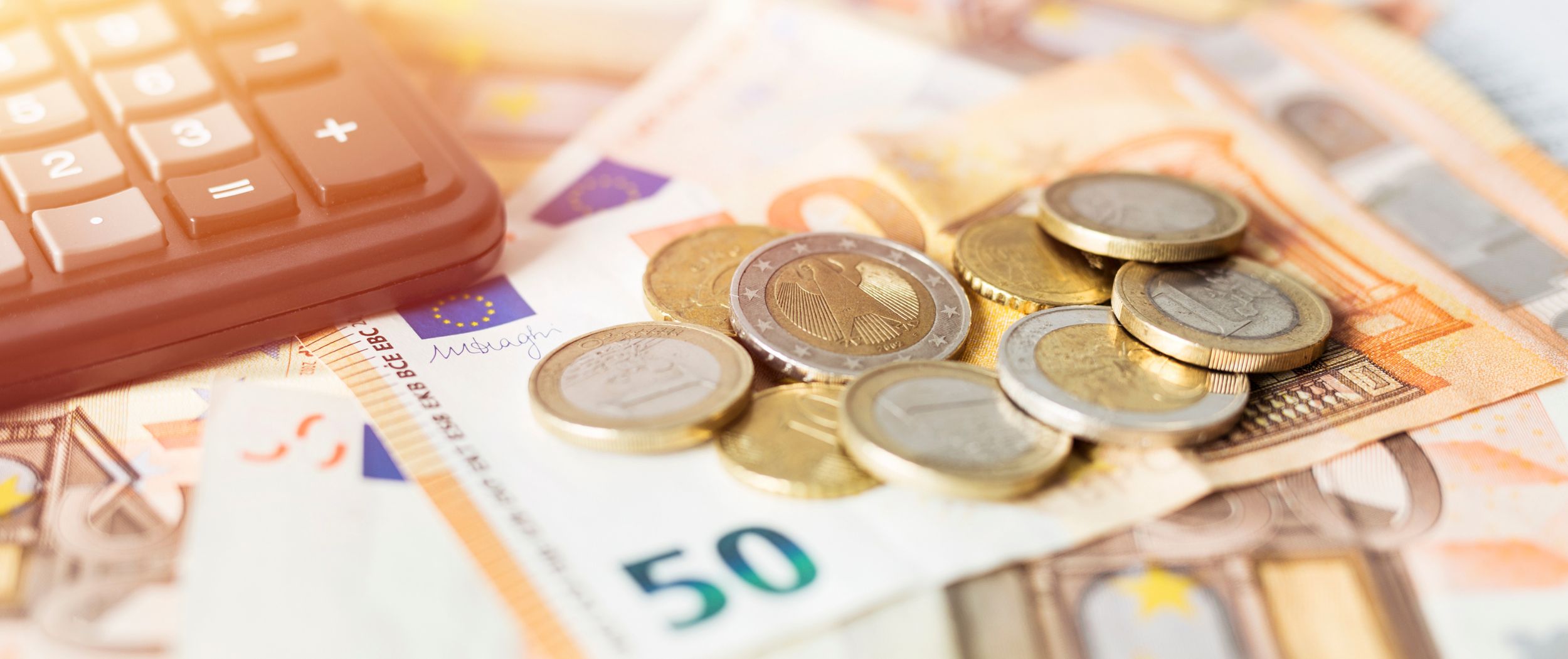 M&uuml;nzen, Euroscheine und ein Taschenrechner liegen auf einem Tisch