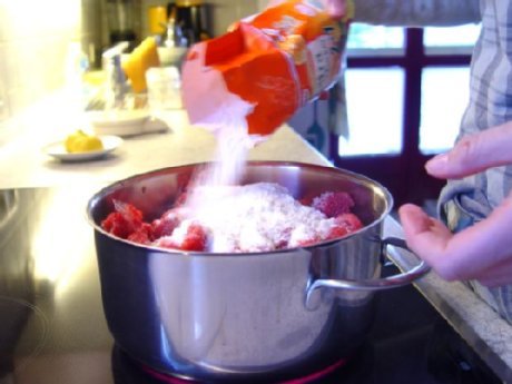 Gelierzucker wird in einen Topf zu roten Fr&uuml;chten gegeben