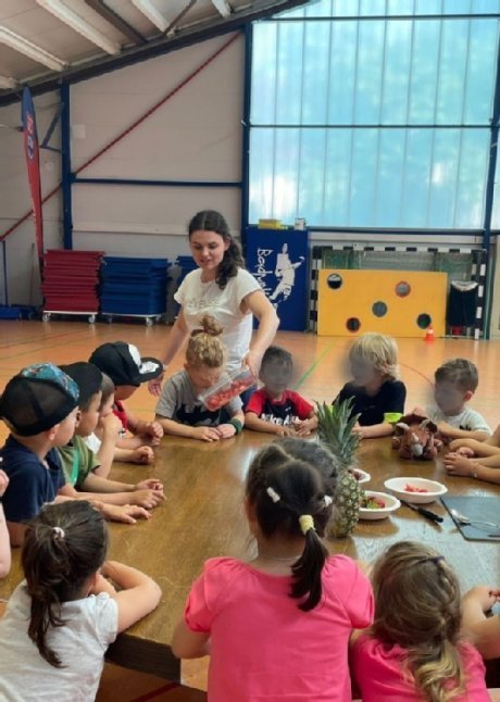 Kinder sitzen um einen Tisch und riechen an Obst 